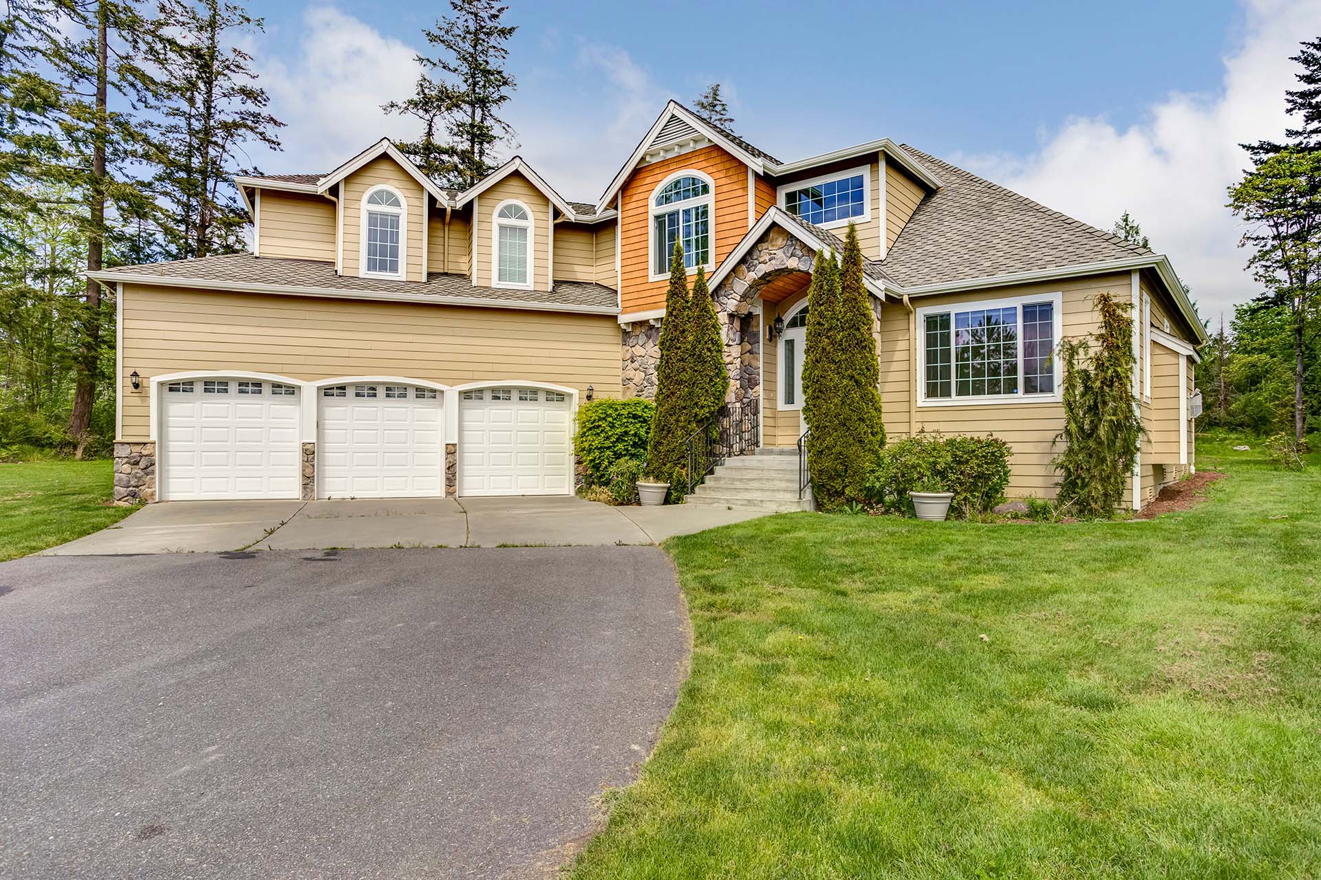 Large home exterior with three car garage spaces.