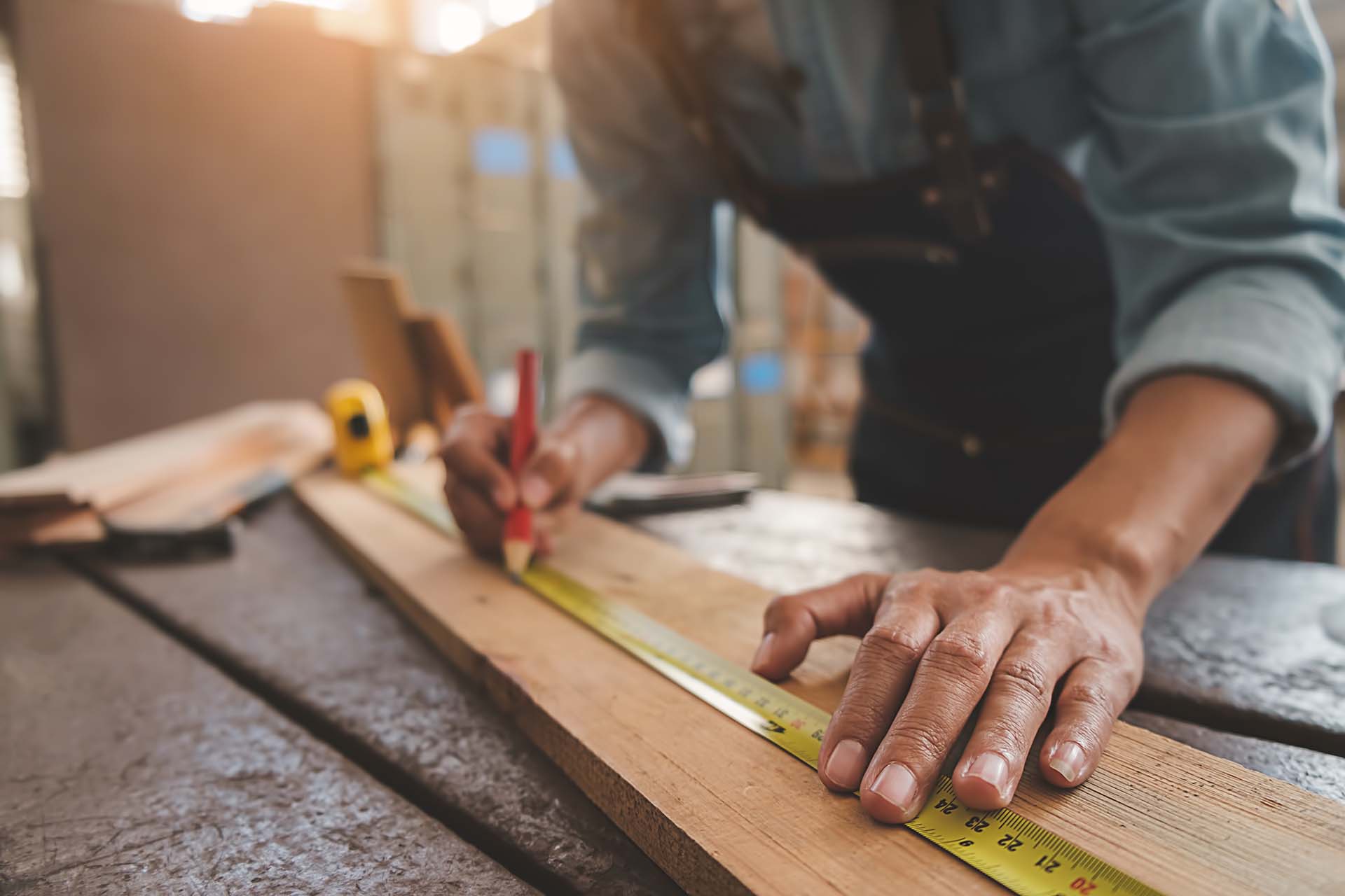 Carpenter working with equipment on wooden table in carpentry