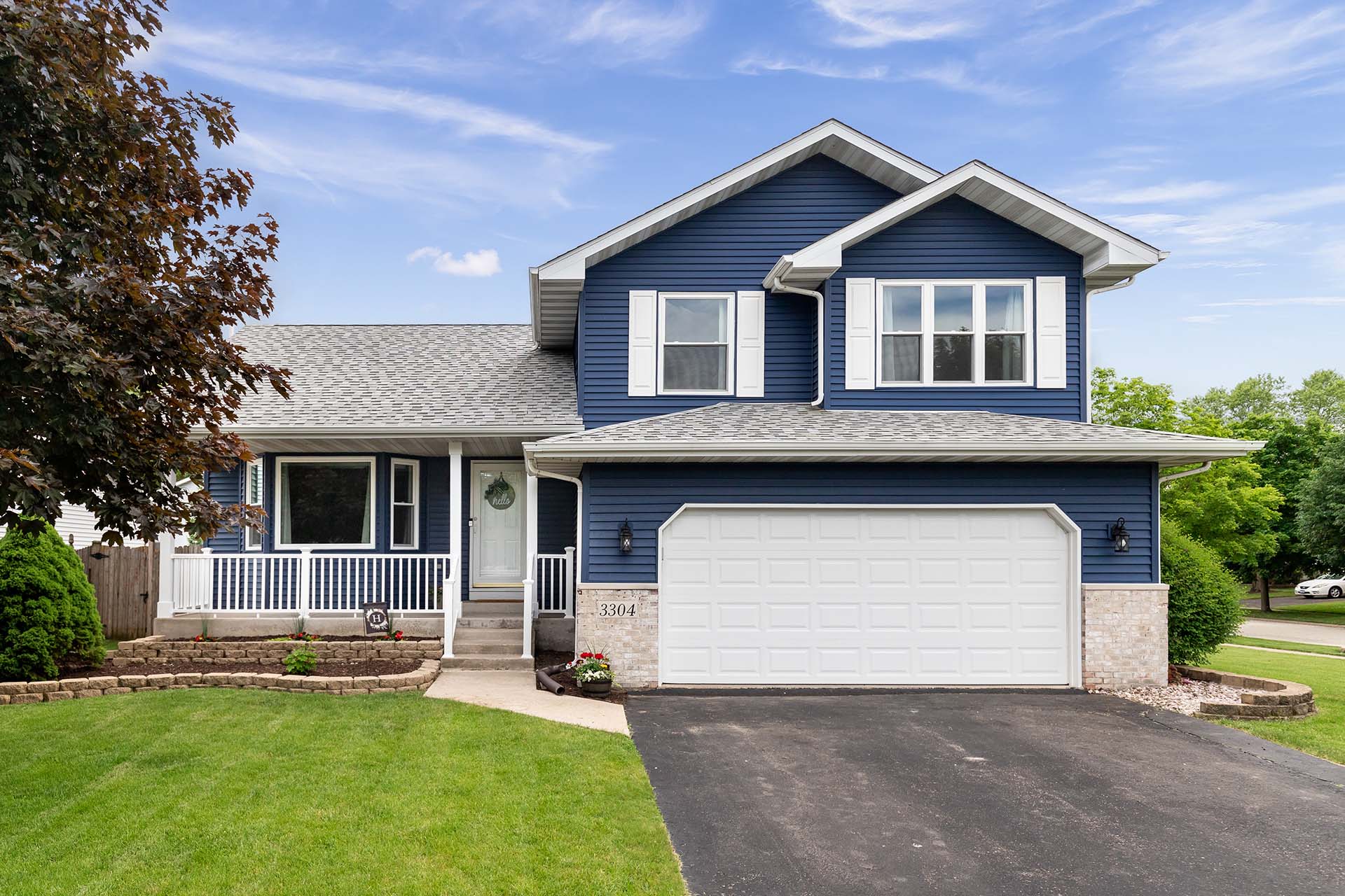 Exterior of a suburban home with blue siding, a white front porc