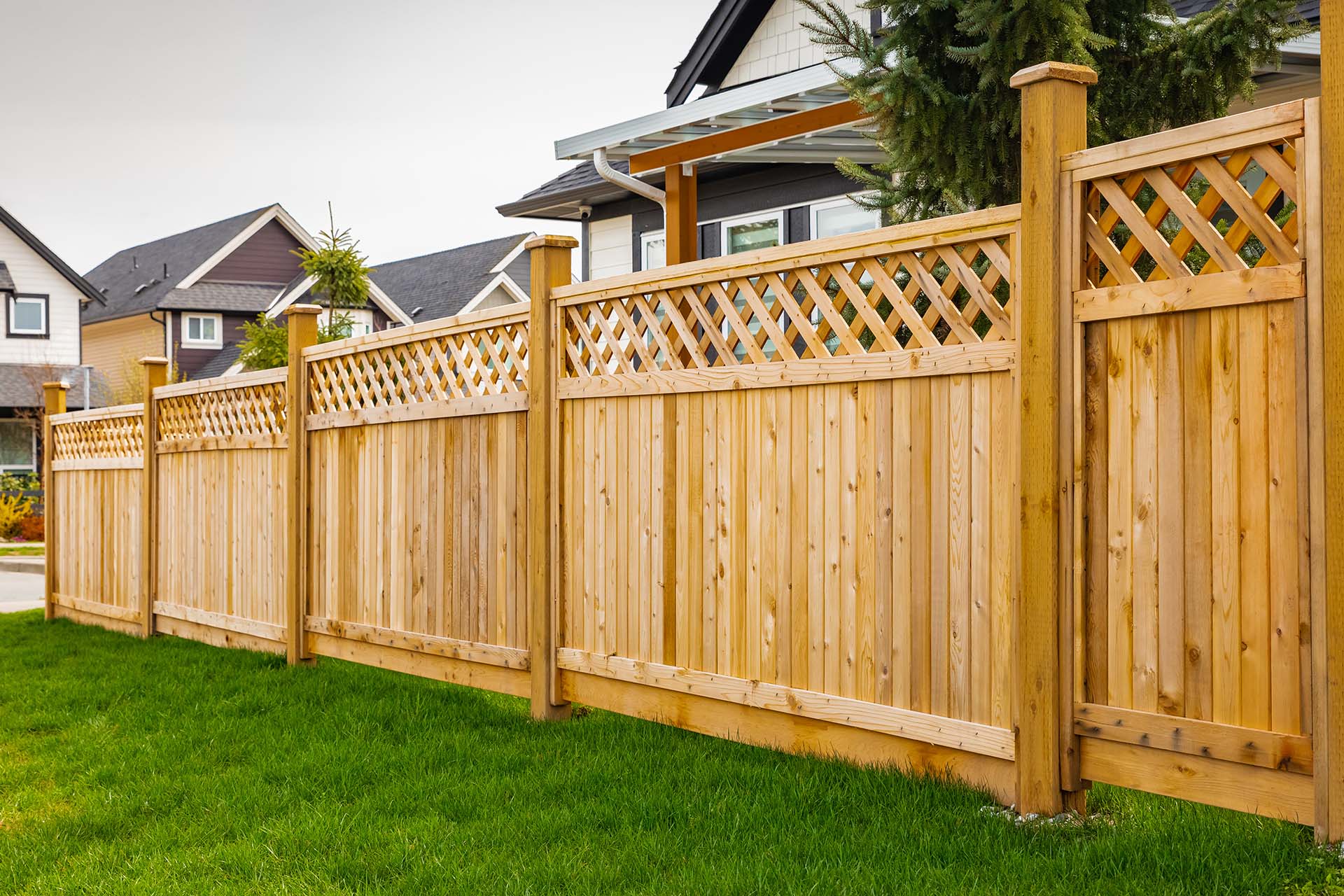 Nice wooden fence around house. Wooden fence with green lawn.