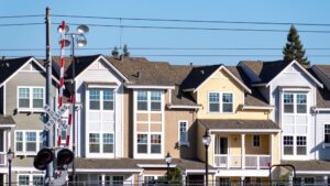 A row of residential buildings near a railroad track showcasing different siding materials.