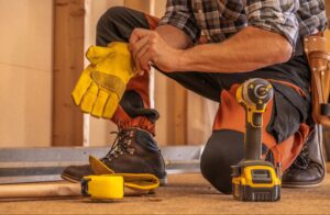 A close-up shot of a handyman putting on protective gloves, with tools laid out in front, ready for the job.