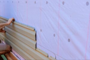 A close-up of a handyman's hands installing vinyl siding.